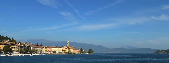 Trip Portugal beliebte Urlaubsziele am Gardasee -  Mit einer Fläche von 370 km² ist der Gardasee der größte See Italiens. Es liegt am Fuße der Alpen und erstreckt sich über drei Staaten: Lombardei, Venetien und Trentino. Die maximale Tiefe des Sees beträgt 346 m, er hat eine längliche Form und sein nördliches Ende ist sehr schmal. Dort ist der See von den Bergen der Gruppo di Baldo umgeben. Du trittst aus deinem gemütlichen Hotelzimmer und es begrüßt dich die warme italienische Sonne. Du blickst auf den atemberaubenden Gardasee, der in zahlreichen Blautönen schimmert - von tiefem Dunkelblau bis zu funkelndem Türkis. Majestätische Berge umgeben dich, während die Brise sanft deine Haut streichelt und der Duft von blühenden Zitronenbäumen deine Nase kitzelt. Du schlenderst die malerischen, engen Gassen entlang, vorbei an farbenfrohen, blumengeschmückten Häusern. Vereinzelt unterbricht das fröhliche Lachen der Einheimischen die friedvolle Stille. Du fühlst dich wie in einem Traum, der nicht enden will. Jeder Schritt führt dich zu neuen Entdeckungen und Abenteuern. Du probierst die köstliche italienische Küche mit ihren frischen Zutaten und verführerischen Aromen. Die Sonne geht langsam unter und taucht den Himmel in ein leuchtendes Orange-rot - ein spektakulärer Anblick.